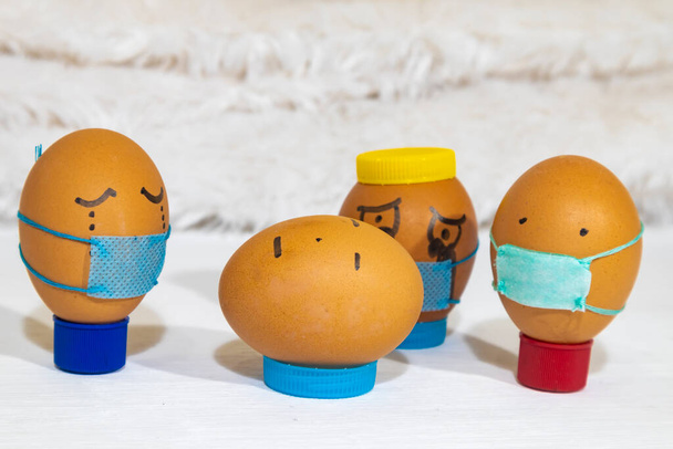 Several painted eggs wearing masks, mourning a dead one who is not wearing mask. Fun indoor activity with children. - Photo, Image
