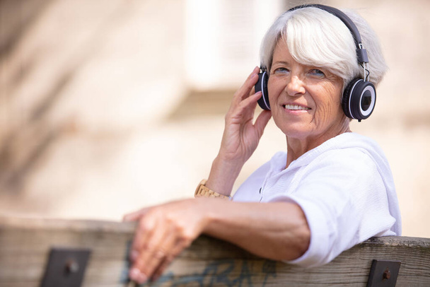 portrait of a mature woman listening music outdoors - Photo, Image