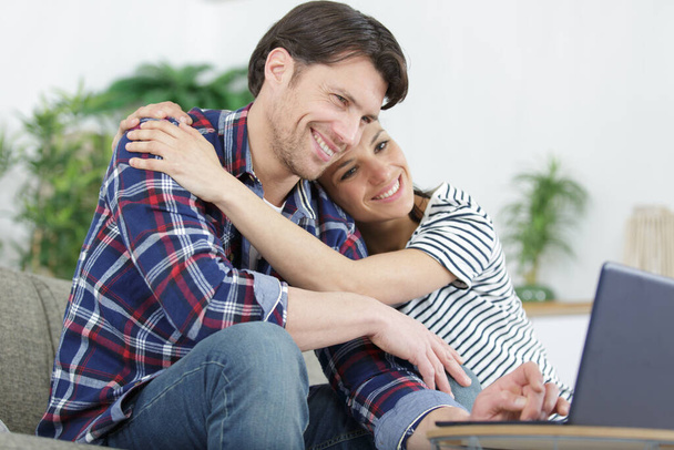 portrait of loving couple with laptop on sofa at home - Foto, Imagen