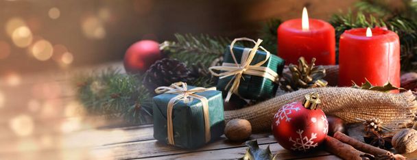 tradycyjna ozdoba świąteczna na drewnianym stole ze świecą i pudełkiem prezentów w panoramicznym widoku  - Zdjęcie, obraz