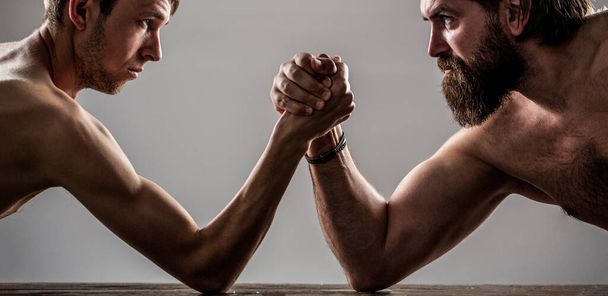 Zwei Männer Hände umklammerten Arm Wrestling, starke und schwache, ungleiche Kampf. Schwer bemuskelte bärtige Mann Armdrücken ein mickriger schwacher Mann - Foto, Bild