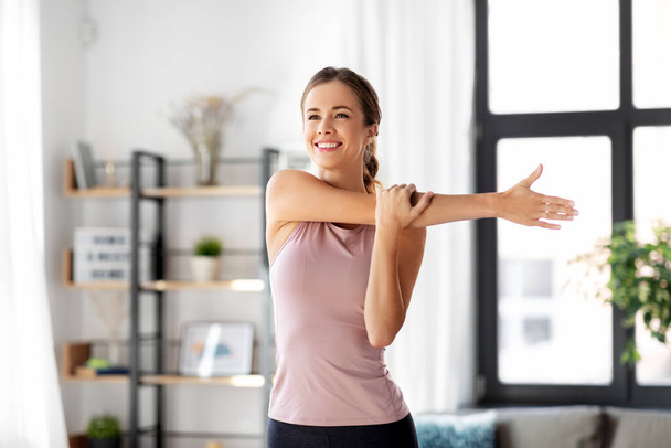 smiling young woman stretching arm at home - Foto, imagen