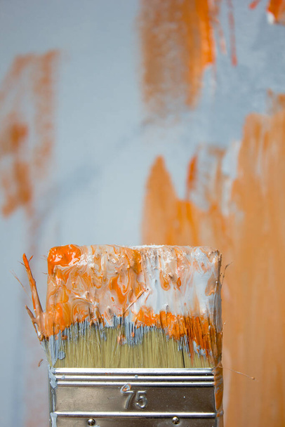 Brosse avec peinture orange et blanche comme rénovation et création. - Photo, image