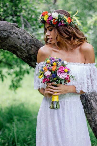 Piękna panna młoda w sukni ślubnej z bukietem kwiatów i nędznikiem - Zdjęcie, obraz
