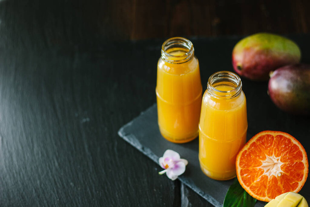 Glass bottles filled by fresh detox mango and orange smoothie. - Foto, Imagen