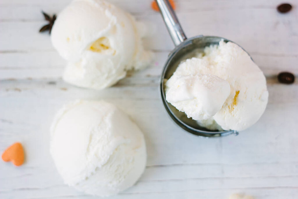 Tablero de madera blanco con cucharada de helado y bolas de helado blanco en él - Foto, Imagen