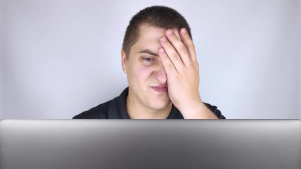 The man looks at the laptop, is embarrassed and ashamed of what he saw there. Expressing emotions and reacting to what you see on the Internet. Shocking content concept. - Footage, Video