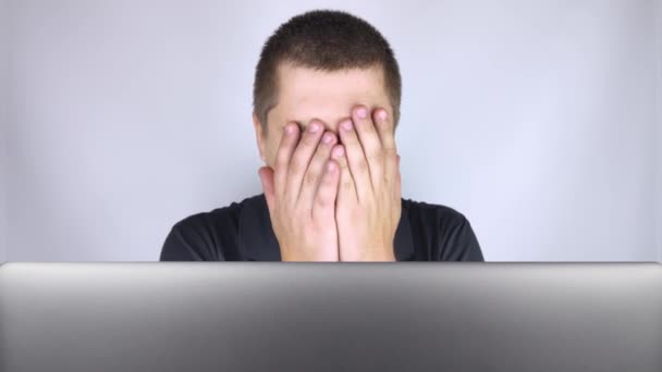 A férfi ránéz a laptopra, zavarban van és szégyelli, amit ott látott. Érzelmeket fejez ki és reagál arra, amit az interneten lát. Sokkoló tartalom fogalma. - Felvétel, videó