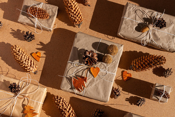 Zero waste Christmas knolling flat lay with hard shadows. Hand crafted eco gift, natural New Year jute decorations top view. Kraft paper wrapping without plastic concept. Orange zest trees heartscones - Photo, Image