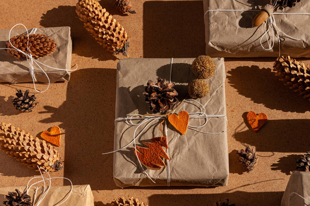 Zero waste Christmas knolling flat lay with hard shadows. Hand crafted eco gift, natural New Year jute decorations top view. Kraft paper wrapping without plastic concept. Orange zest trees heartscones - Photo, Image