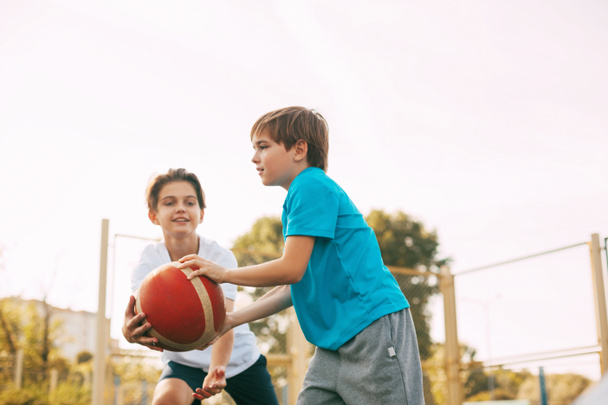 Два хлопчики-підлітки грають у баскетбол на ігровому майданчику. Спортсмени б'ються за м'яч у грі. Здоровий спосіб життя, спорт, мотивація
 - Фото, зображення
