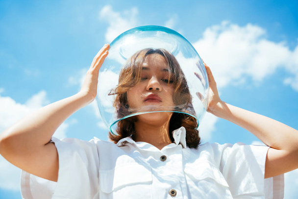 Asian woman wearing glass bowl like astronaut to protect herself from pollution on earth. - Photo, image