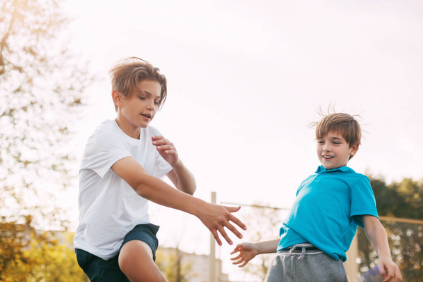 Dwóch nastolatków gra w koszykówkę na placu zabaw. Sportowcy walczą o piłkę w grze. Zdrowy styl życia, sport, motywacja - Zdjęcie, obraz