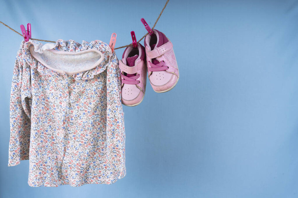 Chemise enfant et chaussures suspendues sur un rack après la lessive sur fond bleu. - Photo, image