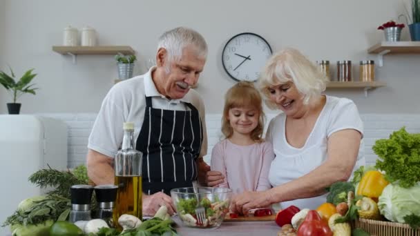 Coppia anziana nonna e nonno in cucina alimentazione nipote bambino con pepe tritato - Filmati, video