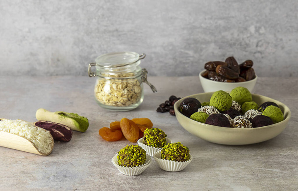 Healthy energy confection balls without artificial sugar, no baking, vegan candy snack made from oats and dry dates, cranberries, apricots with matcha, coconut flakes, and ube powder. - Fotografie, Obrázek