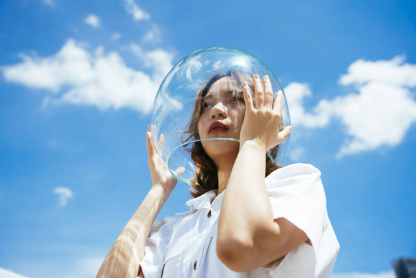 Asian woman wearing glass bowl like astronaut to protect herself from pollution on earth. - Photo, Image