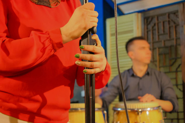 Музыкальная группа выступает на сцене, девушка с микрофоном и барабанщиком на заднем плане - Фото, изображение