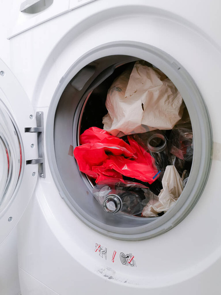 Mikroműanyaghulladék-szennyezést jelentő műanyaghulladékkal töltött mosógép mosás közben - Fotó, kép