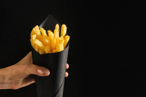 Papas fritas abstractas en cono de papel negro  - Foto, Imagen