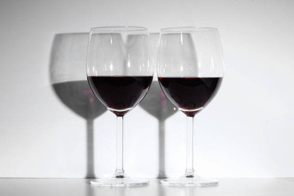 白を基調とした赤ワイングラス2つとテキストのコピースペースがあります - 写真・画像