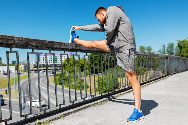 man stretching leg on bridge - Fotoğraf, Görsel