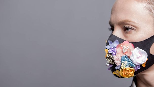 Woman in trendy fashion outfit during quarantine of coronavirus outbreak. Model dressed protective stylish handmade face mask on studio background - Photo, image