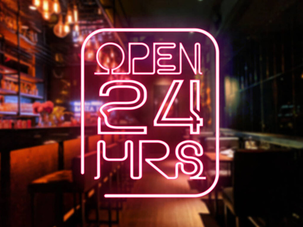 Neon Open 24 tunnin opasteet edessä baarissa tai pubissa. Hieman hämärtynyt baari tai tavernan tausta. Yöelämän käsite. - Valokuva, kuva