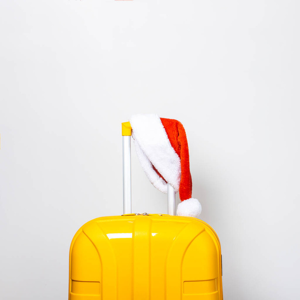 Sarı plastik bir çantada kırmızı bir Noel Baba şapkası takıyor.. - Fotoğraf, Görsel