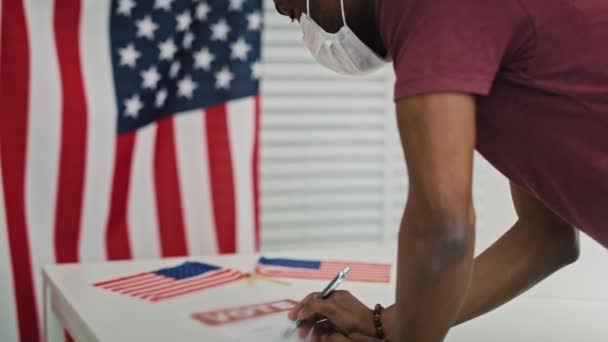 Vídeo de mano del hombre negro votando en máscara facial. Fotografía con cámara de helio RED en 8K. - Metraje, vídeo