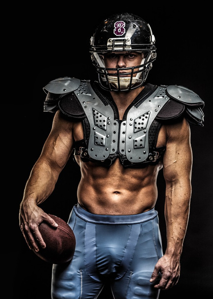 Αμερικανός ποδοσφαιριστής με μπάλα φορώντας κράνος και προστατευτικές ασπίδες  - Φωτογραφία, εικόνα
