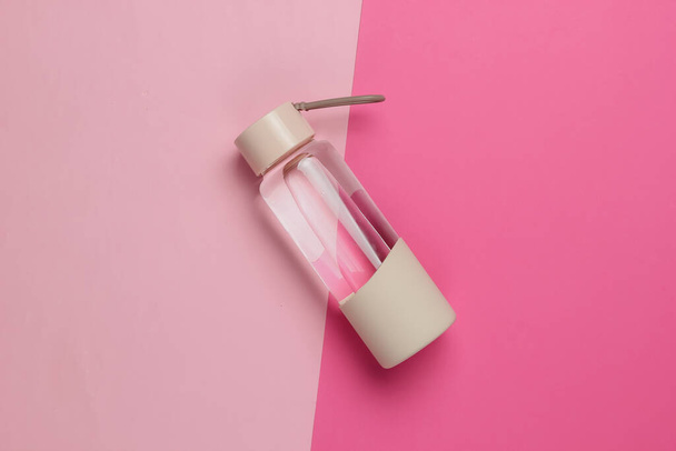 Flasche Wasser für Sport und Outdoor-Aktivitäten auf rosa Pastell Hintergrund. Ansicht von oben - Foto, Bild
