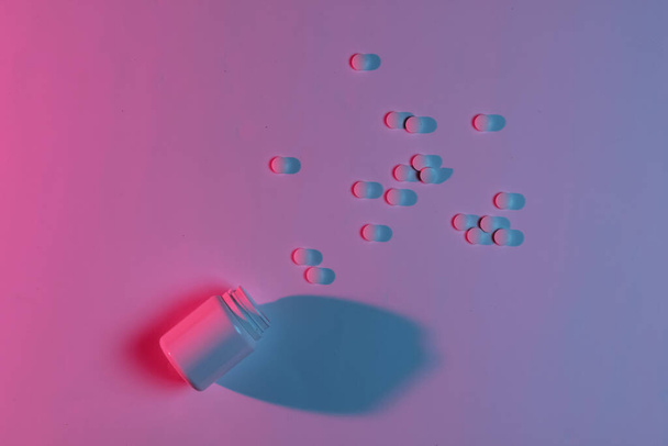 Conceito de medicina. Drogas. Uma garrafa de comprimidos. Luz de noite azul rosa néon - Foto, Imagem