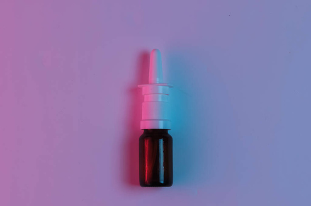 Medicijnconcept. Nosal spray met neon roze blauw nachtlampje - Foto, afbeelding
