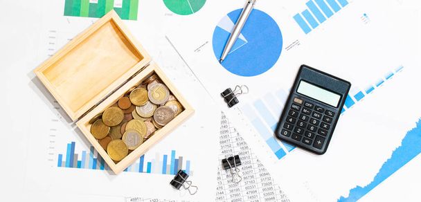 top view of business chart on white wooden table with coins,wood box, calculator and pen, - 写真・画像