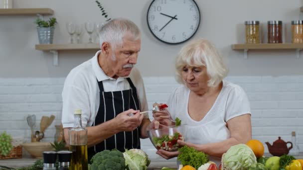Seniorin und Mann füttern sich gegenseitig mit frischem rohen Gemüsesalat. Öko-Ernährung - Filmmaterial, Video
