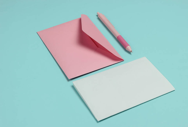 Envelop met een letter en pen op een blauwe pastelachtergrond. Valentijnsdag, bruiloft of verjaardag - Foto, afbeelding