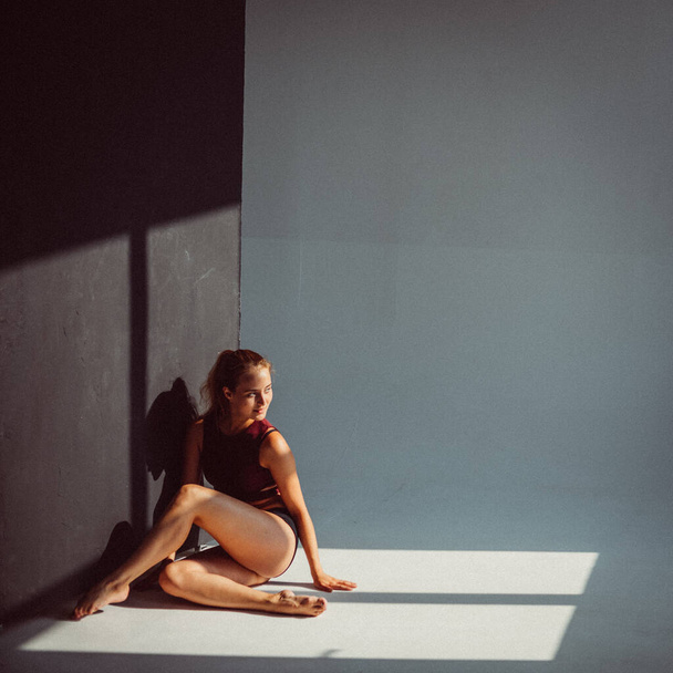 A young girl, a gymnast, with a plastic figure, makes plastic eases on cubes in the studio, sunlight from the window shines on her. - Foto, afbeelding