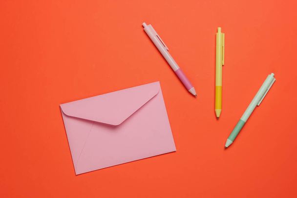 Envelope e canetas coloridas sobre fundo laranja. Vista superior - Foto, Imagem