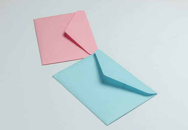 Два конверти рожевого і синього пастельних кольорів на білому тлі. Макет на день святого Валентина, весілля або день народження
 - Фото, зображення