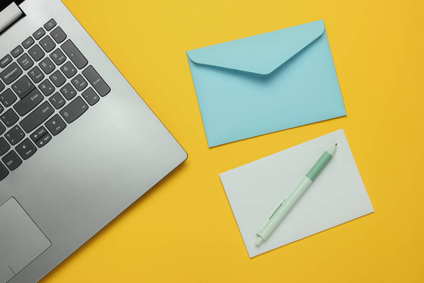 Laptop ve zarf sarı arkaplanlı. Sevgililer Günü. Üst görünüm - Fotoğraf, Görsel