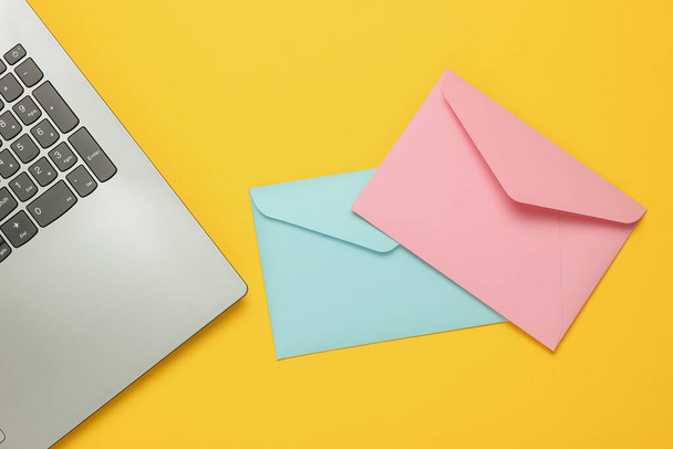 Laptop and envelopes on yellow background. Valentine's day. Top view - Photo, image