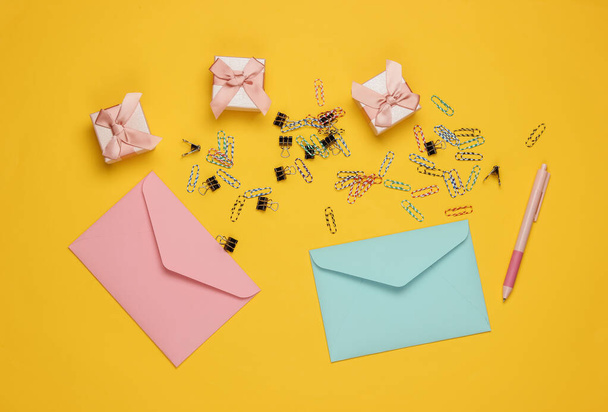 Envelope, gift boxes and paper clips on yellow background. Top view - Fotó, kép