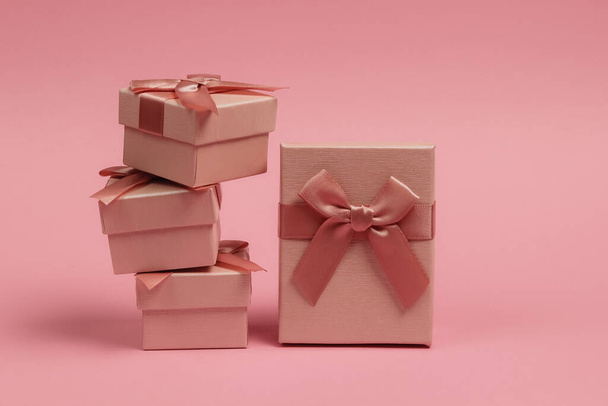 ピンクのパステルの背景に弓とギフトボックスのスタック。クリスマス、誕生日や結婚式のための組成. - 写真・画像