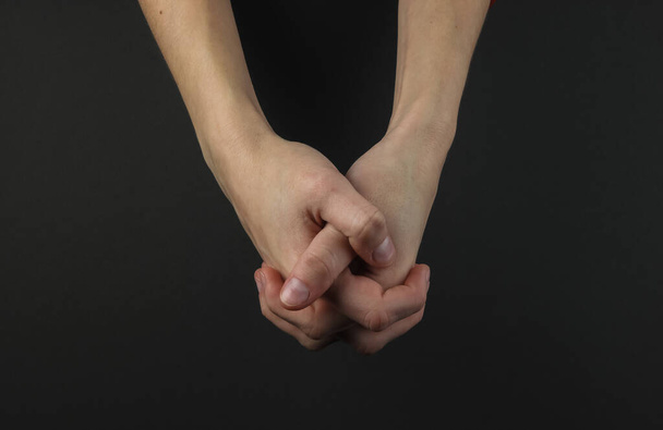 Female hand on a black background. Lock of hands - Zdjęcie, obraz