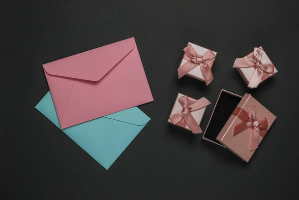 Envelope, boxes of gifts on black background. Christmas, Valentine's day, wedding or birthday. Top view - Foto, Bild