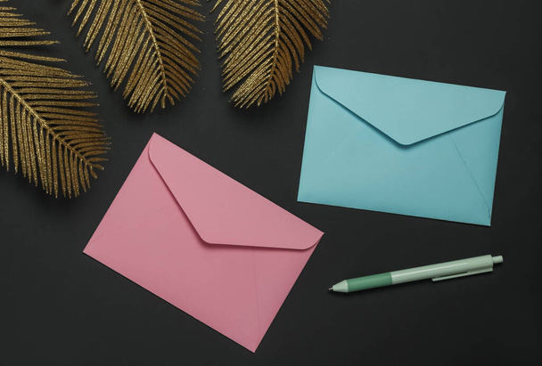Envelopes sobre fundo preto com folhas de palma dourada. Deitado de moda plana. Vista superior - Foto, Imagem