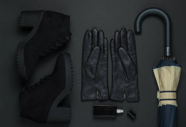Vrouwen mode accessoires op een zwarte achtergrond. Suède laarzen, leren handschoenen, parfumflesje, paraplu. Bovenaanzicht - Foto, afbeelding