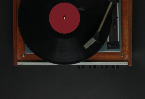 Retro-Musikspieler. Schallplattenspieler mit Schallplatte auf schwarzem Hintergrund. 70er Jahre. Ansicht von oben - Foto, Bild