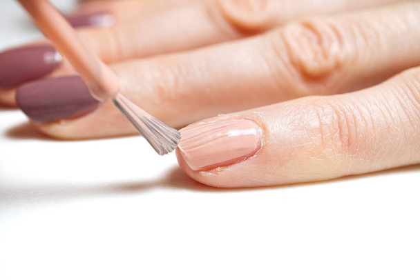 Manicure. Closeup shot of a woman hand polishing nails - manicure. Young caucasian woman receiving a french manicure. Nail technician manicure at nail salon. - 写真・画像